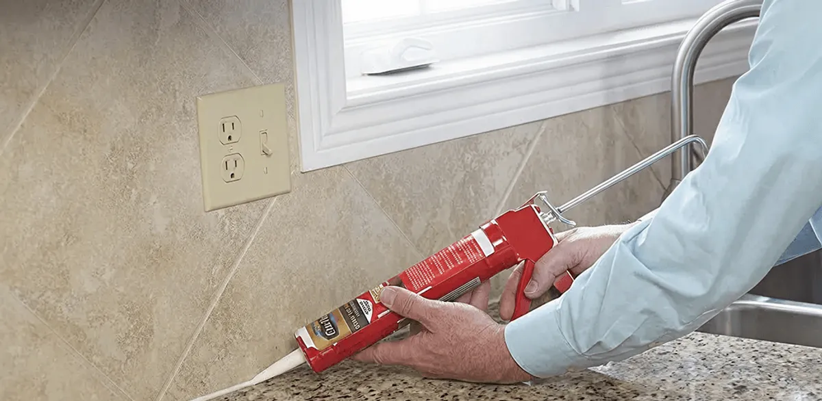 Handyman applying caulk along a kitchen backsplash and countertop seam in South Bend, IN