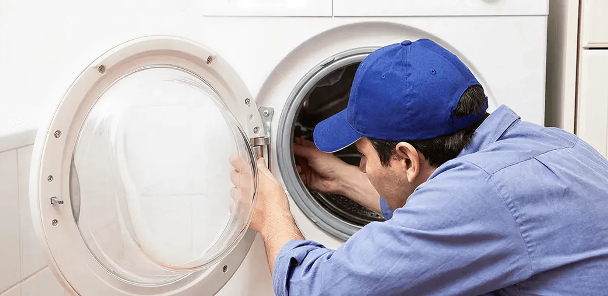 Washing machine repair handyman inspecting a front-load washer drum in South Bend, IN